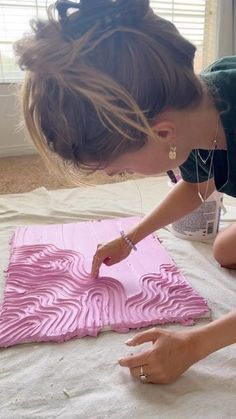 a woman is painting a piece of art on the floor