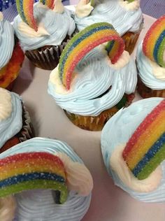 cupcakes decorated with rainbow icing and sprinkles on a plate