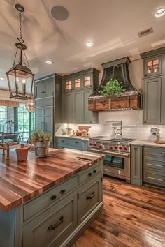 a large kitchen with wooden floors and green cabinets, an island in the middle has a potted plant on it