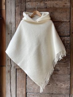 Cream white hooded lambswool poncho cape with fringes Ladies poncho Pure wool hooded ladies poncho Milk White pure wool blanket poncho cape One size fits fashionably for most everyone, short or tall, big or small. This piece is versatile for both Men's & Women's outdoor fashion, and can be used insider in cooler winter weather to keep warm while reading on the couch. CARE: Hand-wash and hang to dry, light iron if needed, or dry clean. MEASURES: Length at the front of the neckline to the bottom is ~90 cm/35 inches, the shoulder length is ~55cm/22 inches; COMPOSITION: 100% lambswool If you like this, bookmark & browse my shop for other items! Save, Share, Pin or Post! Browse the Shop: https://www.etsy.com/shop/Lovetosleep Thank You for visiting! Have a lovely day. Anita from Lovetosleep White Blanket Coat, Luxury Cream Poncho For Winter, White Sweater Poncho, Cheap White Casual Poncho, Luxury Oversized White Poncho, Cheap Fall Poncho Cape, White Winter Poncho Cape, White Cozy Winter Poncho, Cozy White Winter Cape