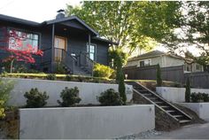 a house with stairs leading up to it and trees in the front yard on either side