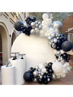 black and white balloons are hanging from the side of a large balloon arch in front of a building