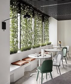 an indoor dining area with white tables and green plants on the wall