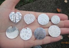 a person is holding seven different sized leaf pendants