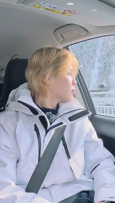 a woman sitting in the back seat of a car wearing a white jacket and black tie