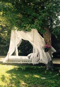 a white canopy bed sitting under a tree