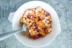 a white bowl filled with cereal on top of a gray table next to a spoon