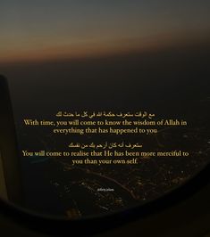 an airplane window view looking out at the city lights and buildings with arabic writing on it