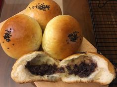 three buns with raisins on them sitting on a cutting board