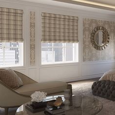 an elegant bedroom with white walls and beige curtains on the windowsills, along with a large round glass coffee table