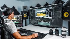 a man sitting at a desk in front of a computer monitor with sound mixing equipment on it