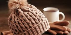 a knitted hat and mittens sitting on top of a table next to a cup of coffee