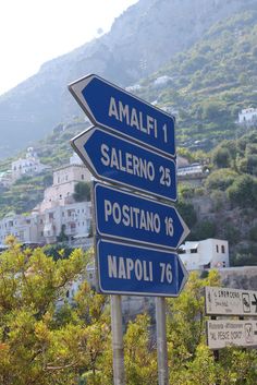 there are many street signs on the side of the road that point in different directions