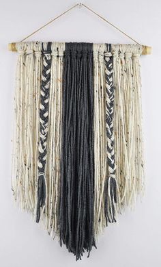 a black and white wall hanging with fringes on it's sides, made out of yarn