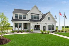 a large white house sitting on top of a lush green field next to a flag pole