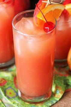 two glasses filled with orange juice and garnished with cherries