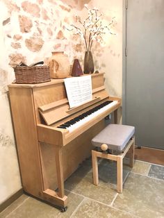 a piano and stool in front of a stone wall with a sign on it that says,