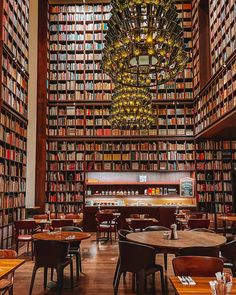 a library filled with lots of books next to a chandelier hanging from the ceiling