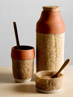 a brown and white vase sitting next to a cup on top of a table