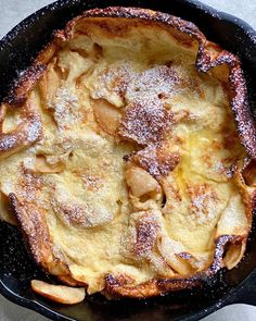 a skillet filled with food covered in powdered sugar on top of a table