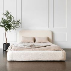 a white bed sitting next to a potted plant