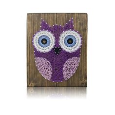 an owl made out of string on a wooden board with blue eyes and purple yarn