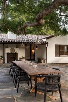 a wooden table sitting under a tree next to a building