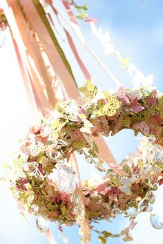 a close up of a wreath hanging from a pole with ribbons and flowers on it