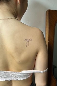 womens back of shoulder blade handpoked tattooed of a ribbon bow very small with black and grey ink handpoked fresh light pink lacey bra gold necklace and earrings Dragon Tattoo Ideas, Aesthetic Tattoos, Cute Little Tattoos, Cute Tiny Tattoos