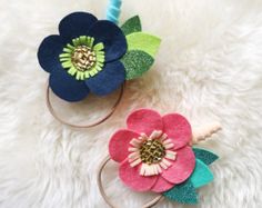 two flower headbands are laying on a white furnishing with blue, green and pink flowers