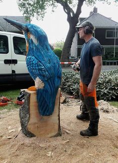 a man standing next to a blue bird statue