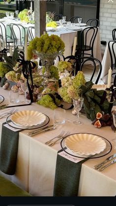 the table is set with plates, silverware and green centerpieces on it