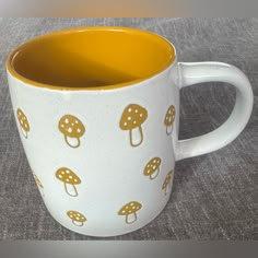 a white and yellow coffee mug with mushrooms on it