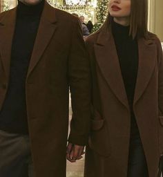 a man and woman are walking down the street together, one is wearing a black turtle neck sweater