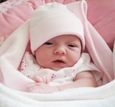 a baby in a pink blanket and hat