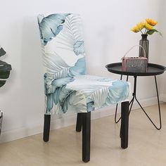 a blue and white chair sitting next to a table with a vase on top of it