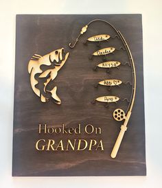 a wooden sign that says hooked on grandpa with fish and lures attached to it