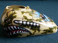 a close up of a helmet on the ground with a shark's mouth painted on it