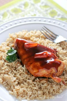 a white plate topped with rice and meat covered in sauce