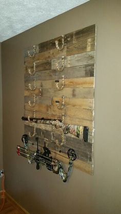 a wooden wall hanging on the side of a wall with hooks and chains attached to it