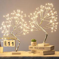 a table topped with books and a lighted tree next to a clock on top of it