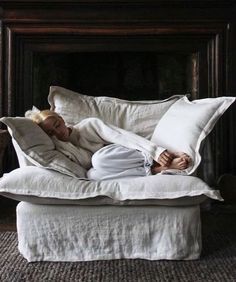 a woman laying on top of a white couch