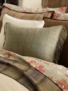 a close up of a bed with pillows and blankets on top of it's headboard