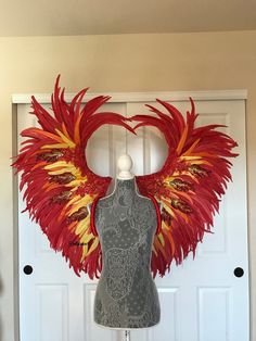 a mannequin with red and yellow feathers on it's head next to a white door