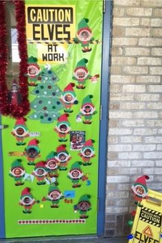 a door decorated with christmas decorations and an elf's hat on it, next to a sign that says caution elves at work