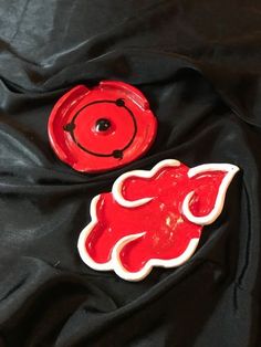 two red and white ceramic objects laying on a black cloth, one is shaped like an elephant