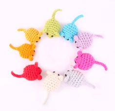 six crocheted mice arranged in a circle on a white background, with one cat looking at the camera