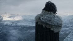 a woman standing on top of a mountain looking at the snow covered mountains behind her