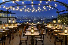 an outdoor dining area with lights strung from the ceiling and tables set up for dinner