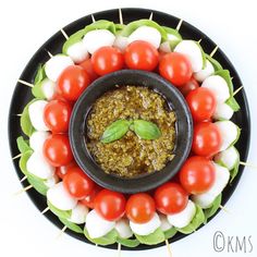 a black plate topped with tomatoes and mozzarella